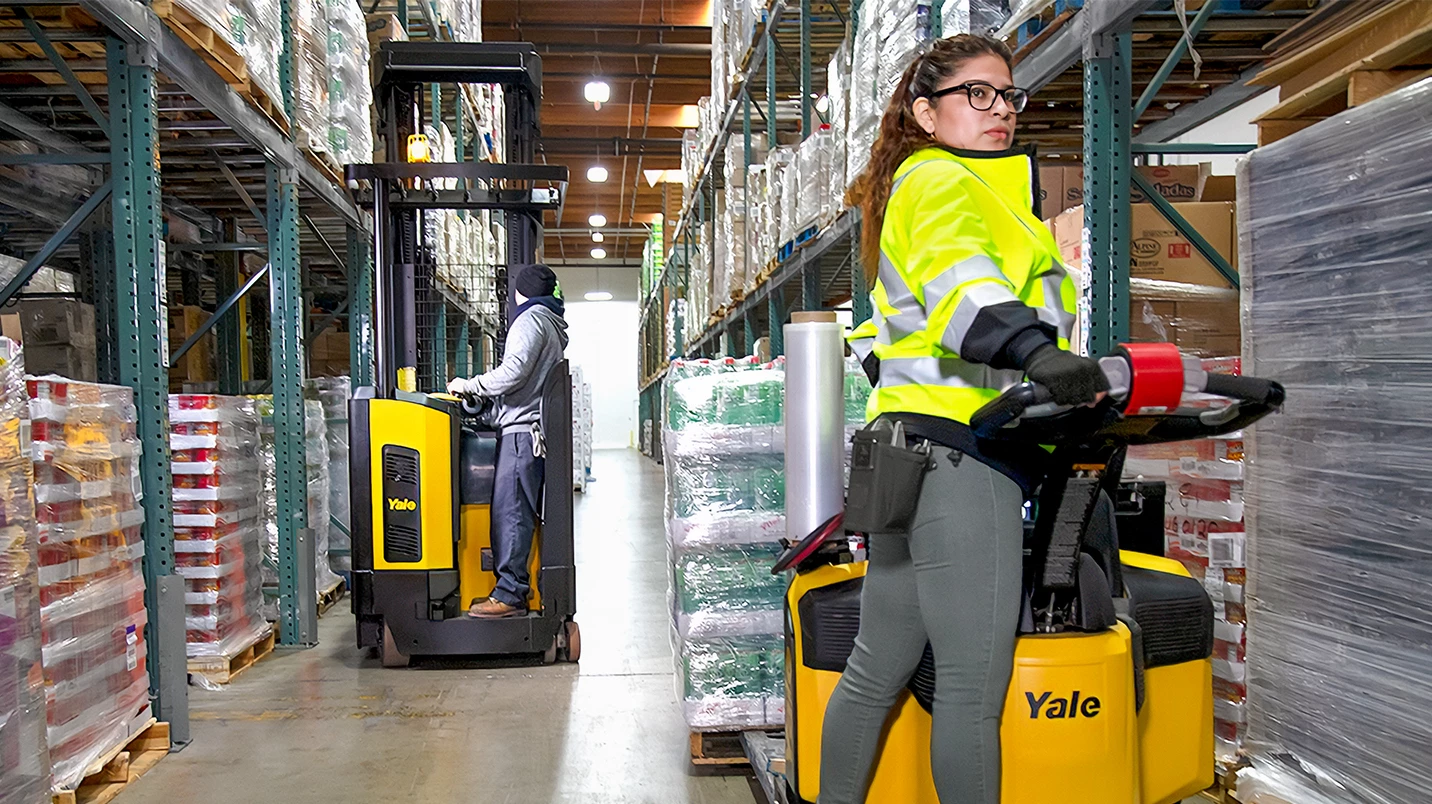 Worker riding lift truck in warehouse.